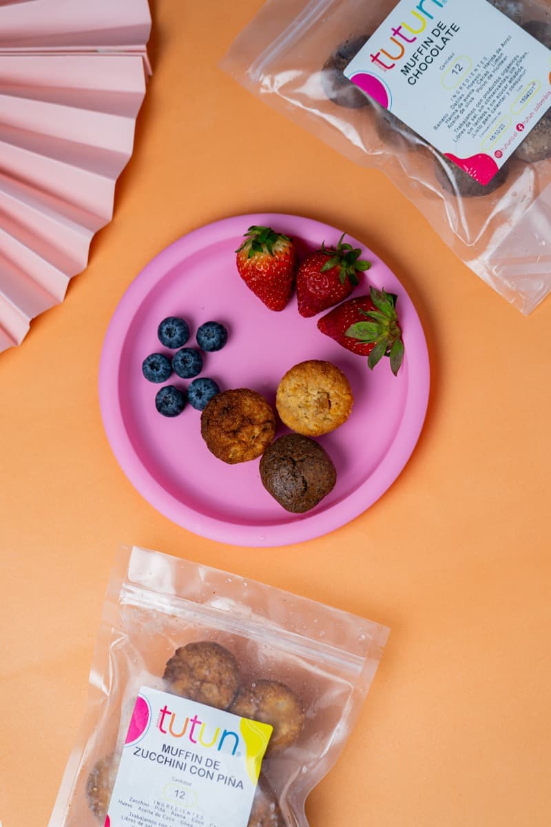 Muffins TUTUN servidos en plato rosa con fresas y arándanos